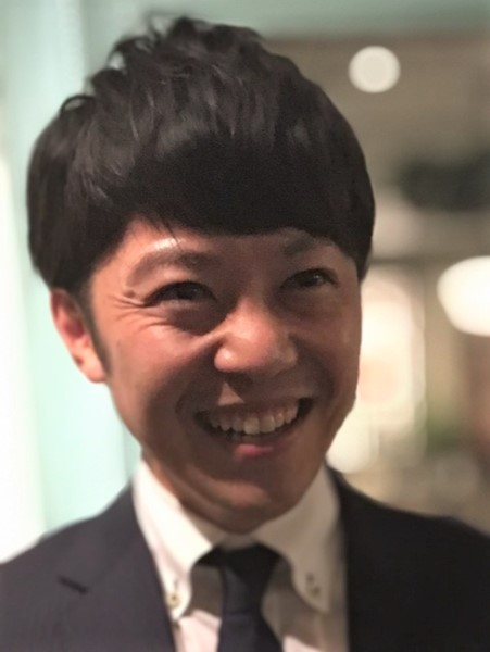 室内でスーツとネクタイを着た微笑む男性。