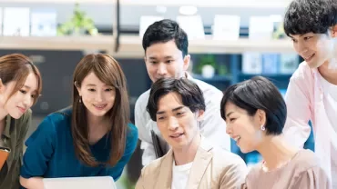 オフィスでノートパソコンを見る6人のグループ。
