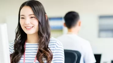 オフィスでパソコンに向かって微笑む女性。