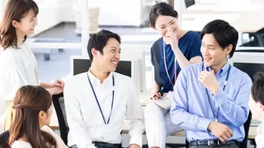 オフィスで笑顔で話している同僚のグループ。