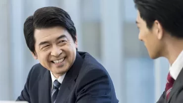 スーツ姿のビジネスマン2人が会話を楽しんでいる。