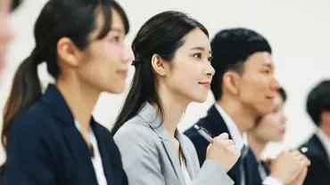会議で話を聞いている人々の列。