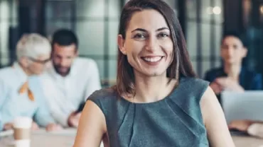 ビジネス会議でグレーのドレスを着た笑顔の女性。