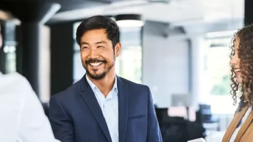 現代的なオフィスで微笑みながら握手をする人々。