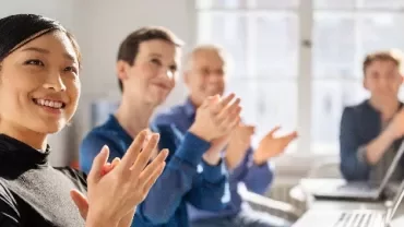 明るいオフィスで拍手する人々。
