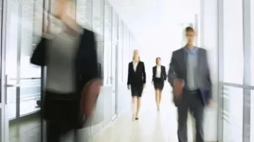 オフィスの廊下を歩く人々のぼやけた画像。