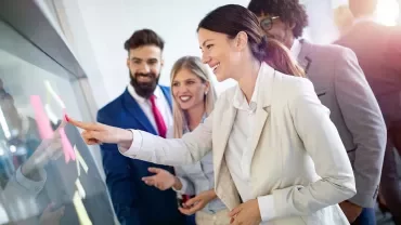 Group of professionals brainstorming with sticky notes on a glass board.