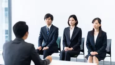 Business meeting with three people sitting across from a person in a suit.
