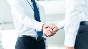 オフィスで握手する二人のビジネスパーソン。