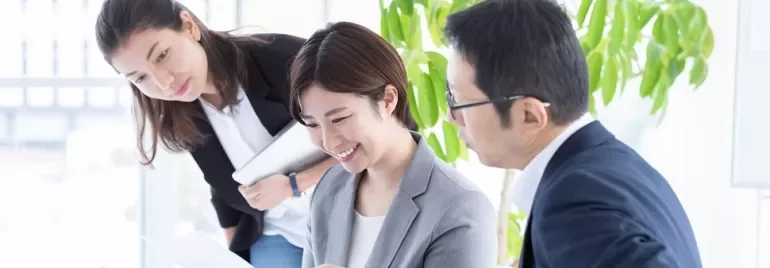書類を見ながら会議している3人のビジネスパーソン。