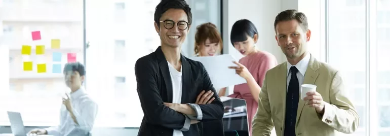 オフィスで笑顔の男性と仕事をするチーム。