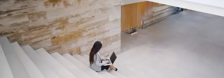 タブレットを持って微笑む人物、背景にカラフルな付箋。