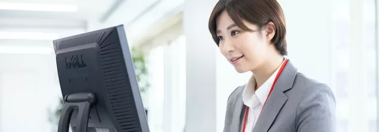 明るいオフィスでコンピューターを使うビジネスウーマン。