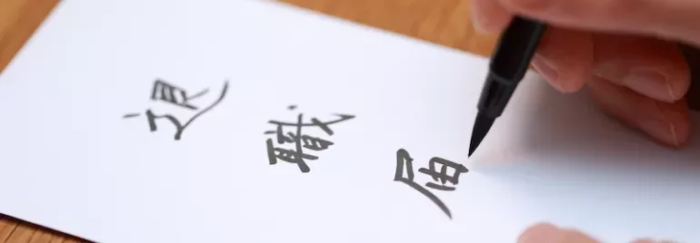 ペンで紙に日本語の文字を書く人。