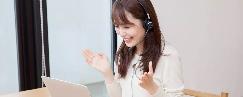 Woman wearing headset smiling during a video call on laptop.