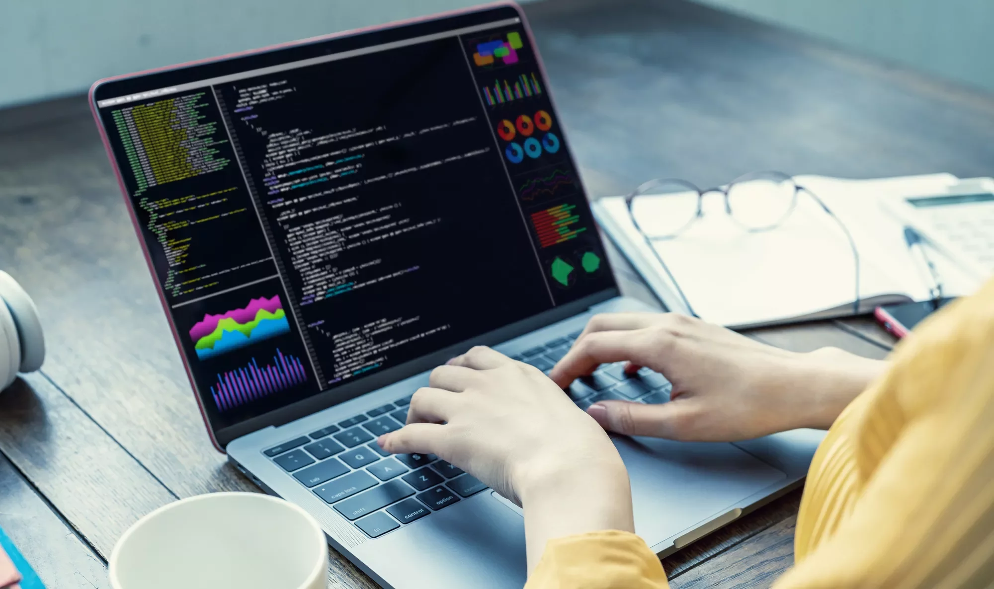 ノートパソコンでコードを入力し、画面にはデータのチャートが表示されている。