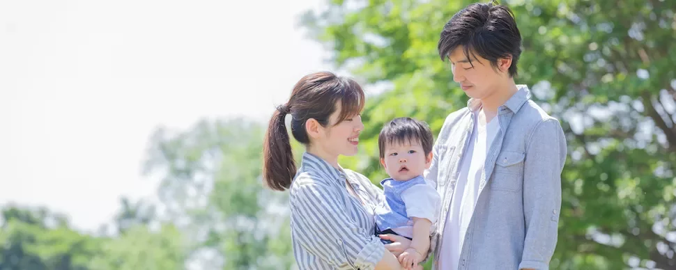 晴れた日、屋外で微笑む赤ちゃんと家族。