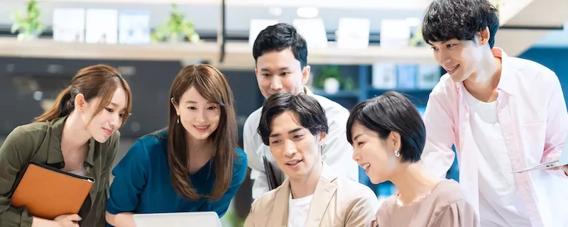 オフィスでノートパソコンを見る6人のグループ。