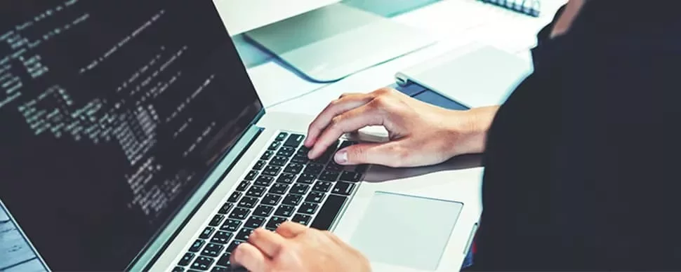 コードが表示された画面でラップトップを操作する人