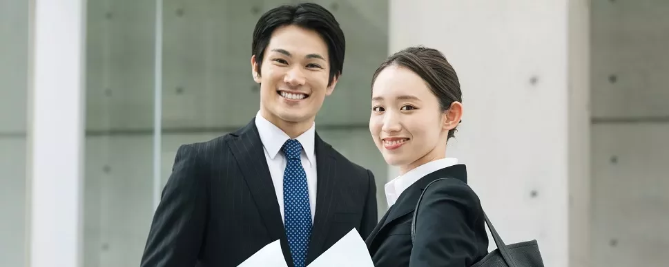 書類を持つビジネススーツ姿の笑顔の男女。