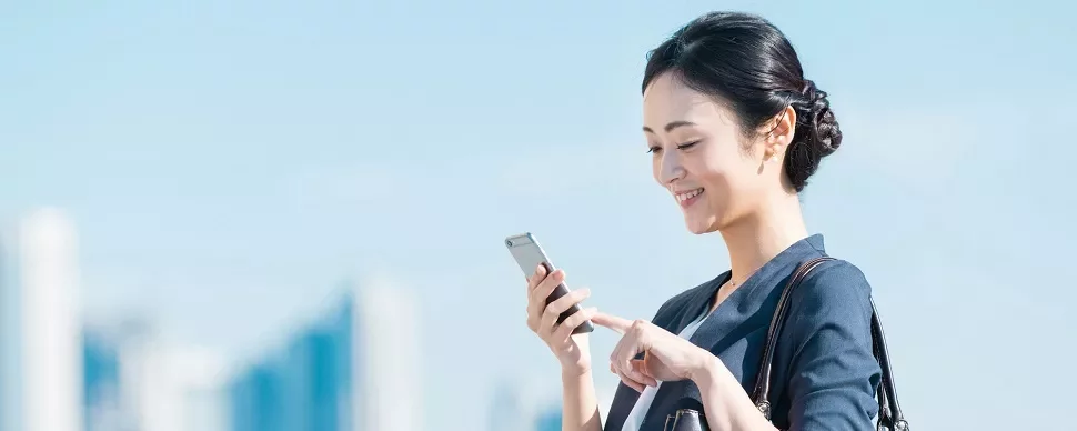 スマートフォンを見ながら笑顔の女性。