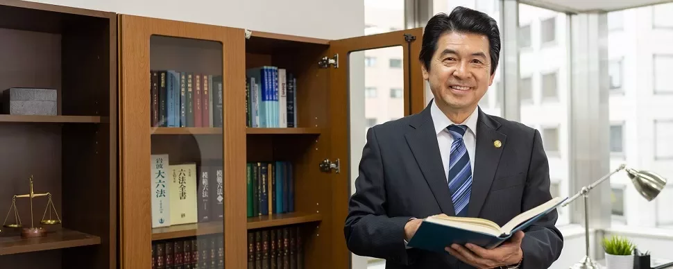 オフィスで本を手に持つスーツ姿の男性。