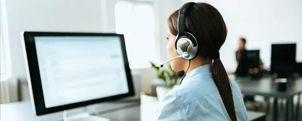 オフィスでコンピューターを使っているヘッドセットを装着した女性。