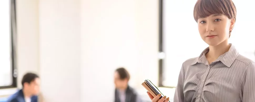 オフィスで携帯電話を持つ女性。