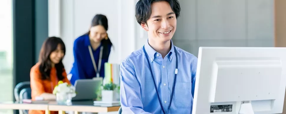 オフィスでパソコンを使っている笑顔の男性。