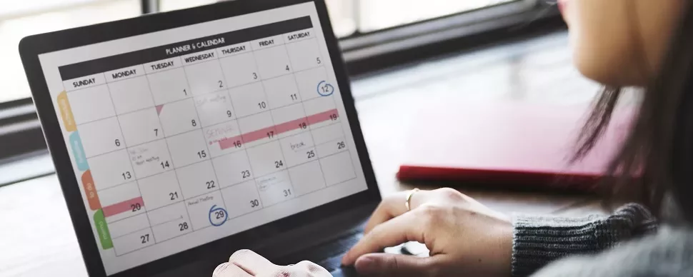 Person using a laptop to view a digital calendar with marked events.