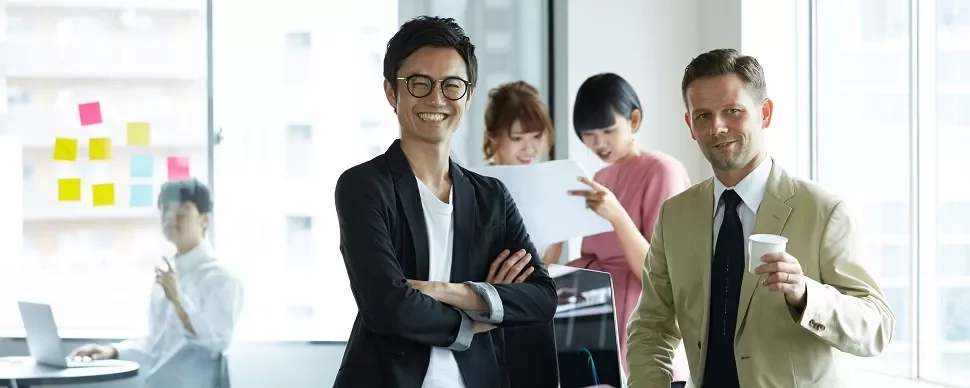 オフィスで笑顔の男性と仕事をするチーム。
