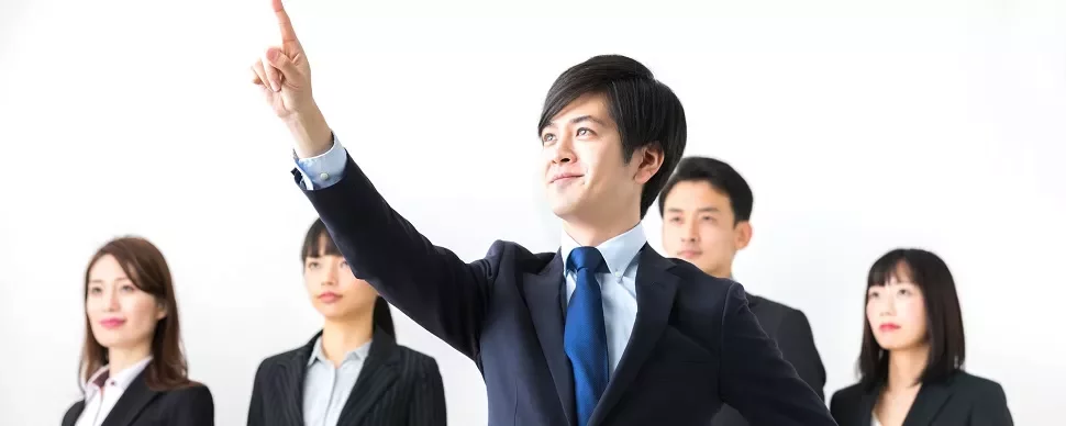 自信を持って手を挙げるビジネススーツ姿の男性と同僚たち。