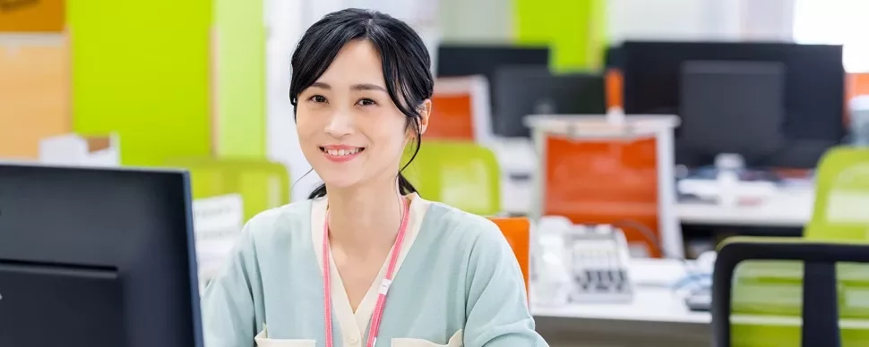オフィスで机に座って笑っている女性。