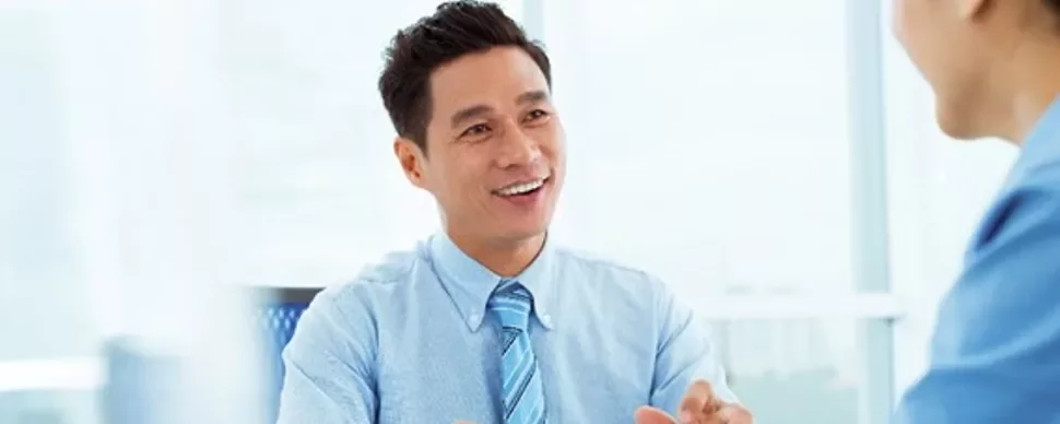 会話中に微笑む青いシャツを着た男性。