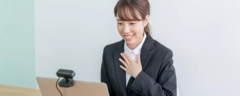 オンラインビデオ通話中に微笑むスーツ姿の女性。