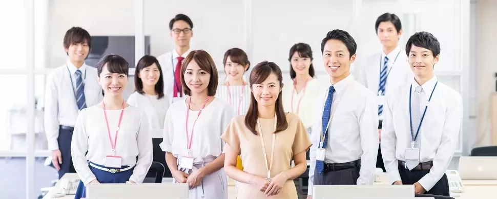 明るいオープンプランのオフィスで微笑む会社員のグループ。