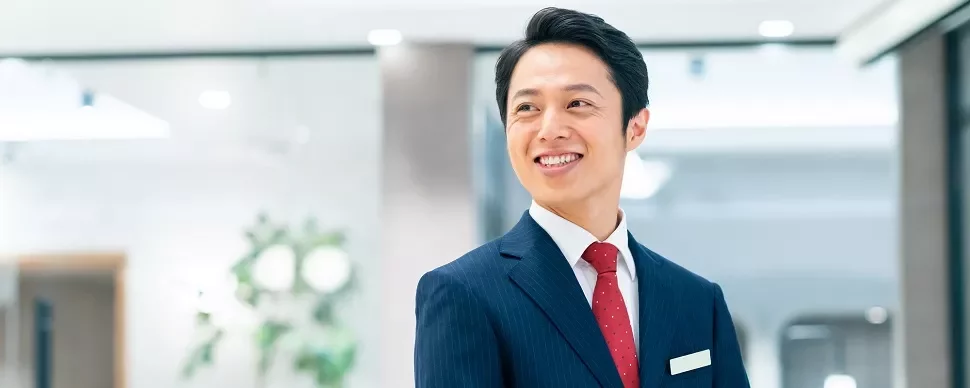 スーツ姿の男性が屋内で微笑んでいる。