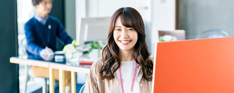 職場でパソコンを使って微笑む女性