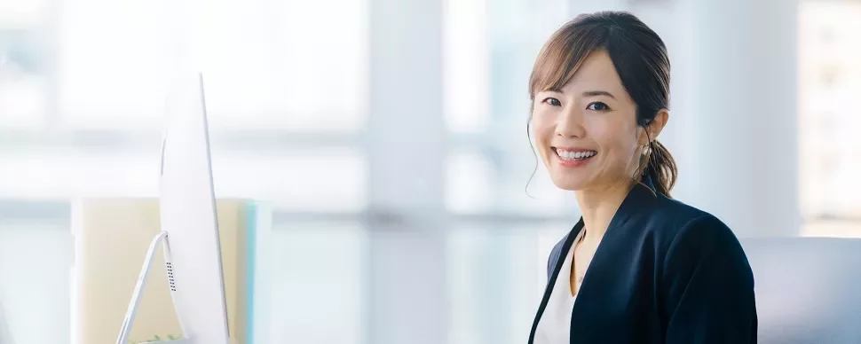 コンピュータを使いながら微笑む女性。