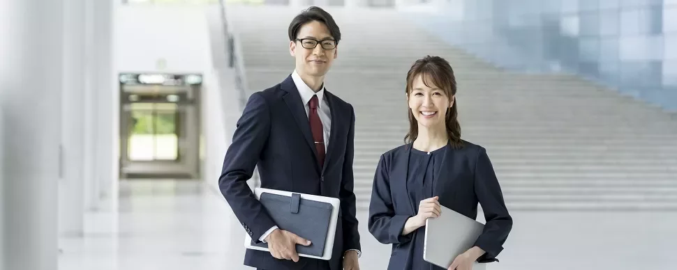 現代のオフィスビルで微笑む二人のプロフェッショナル。