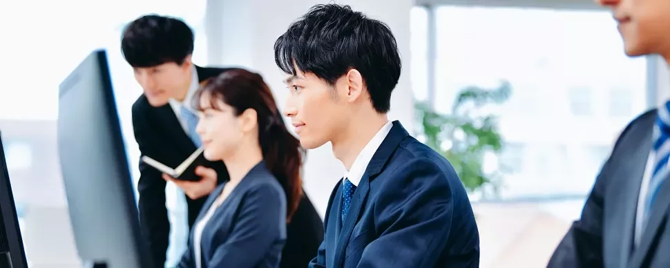オフィスでコンピュータに向かうプロフェッショナルのグループ。