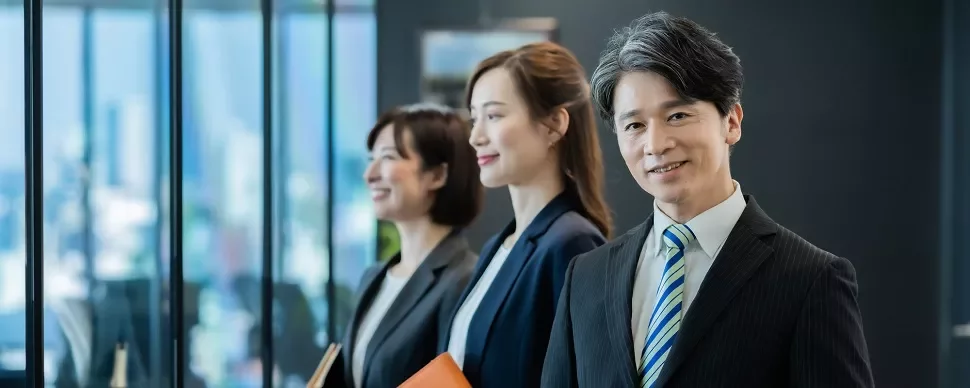 オフィスで微笑む三人のビジネスプロフェッショナル。