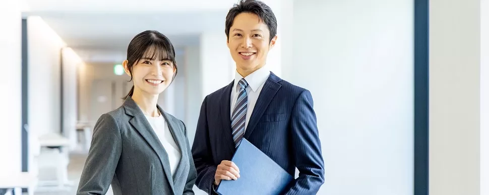 オフィスの廊下で笑顔のビジネスプロフェッショナル二人。