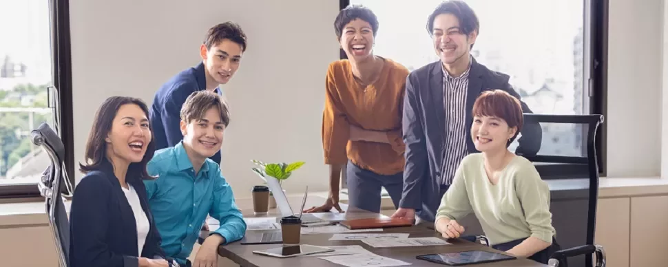会議のテーブルで微笑む6人の多様なグループ。