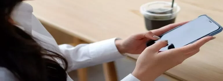 女性が屋外で笑顔で電話中。