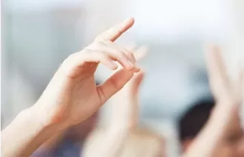 Raised hands in a classroom setting.