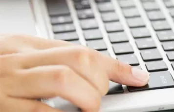 A person typing on a laptop keyboard.