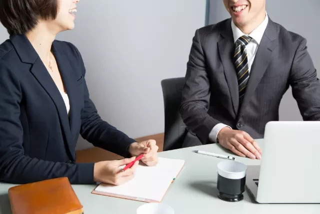 Two people having a meeting with a laptop and notebooks.