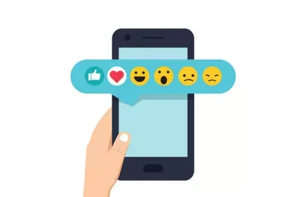 Hand holding smartphone with emoji reactions displayed above.
