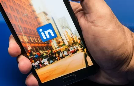 Person holding smartphone with LinkedIn logo on screen.